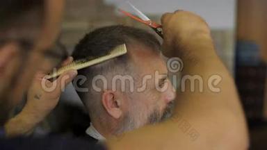 美发师在专业美发沙龙的皇冠客户上用剪刀剪头发。 一个头发花白的男人